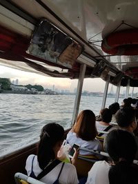 Rear view of people sitting in ferry sailing on sea