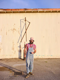 Man working with umbrella standing against wall