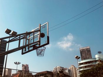 Low angle view of basketball hoop in city against blue sky