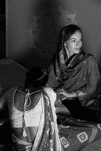 Indian artisan is applying mehndi on the hands of a white skin bride wearing a saree.