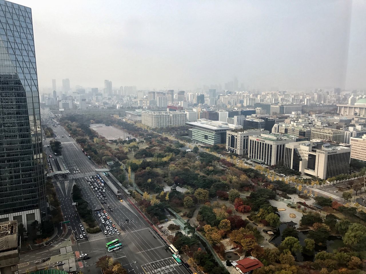 building exterior, cityscape, architecture, city, aerial view, high angle view, skyscraper, outdoors, crowded, travel destinations, tree, built structure, urban skyline, fog, sky, illuminated, day, downtown district