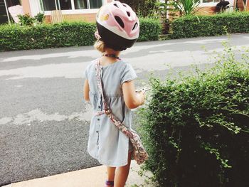 Girl wearing helmet while standing by plants