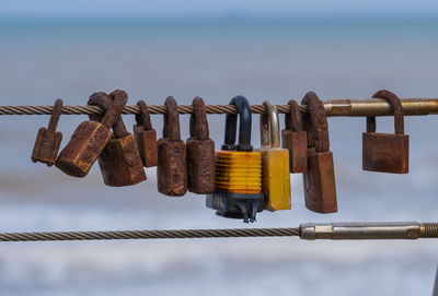 Close-up of padlocks on railing against sky