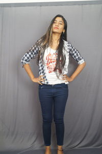 Portrait of young woman standing against wall