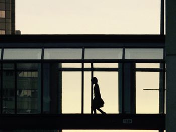 Silhouette woman on window against clear sky