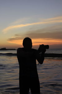 Man standing on beach against sky during sunset