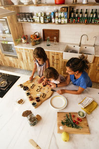 Mother and daughters preparing food in kitchen at home