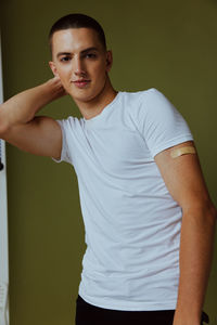 Portrait of young man standing against wall