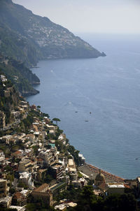 Residential district on mountain by sea against clear sky