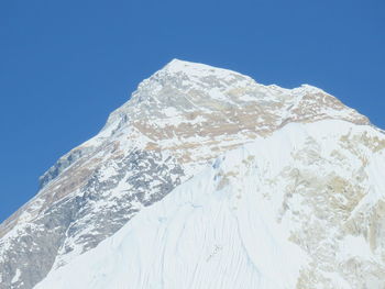 Low angle view of snowcapped mountain against clear blue sky