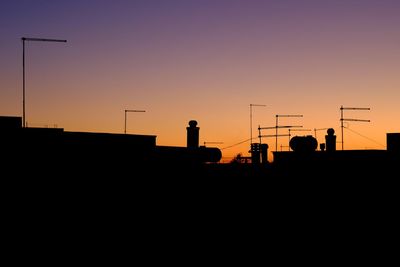 Silhouette of telephone pole against orange sky