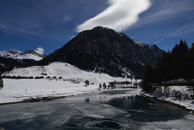 Scenic view of lake by snowcapped mountain against sky