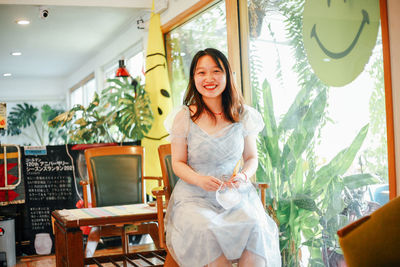 Portrait of young woman standing by window