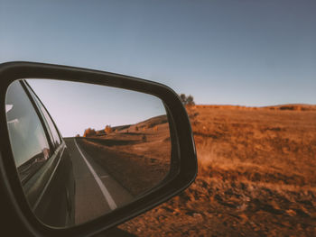 Road seen through side-view mirror of car