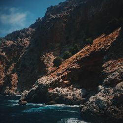 Scenic view of sea by mountains against sky