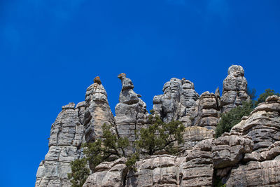 Low angle view of rock formation against clear blue sky