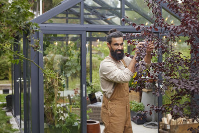 Portrait of young man standing in greenhouse