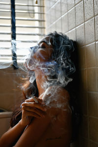 Seductive woman smoking cigarette in bathroom
