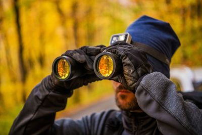 Close-up of mid adult man looking through binoculars in forest