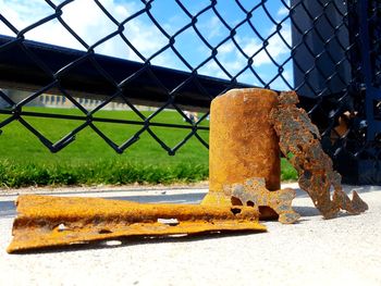 Close-up of rusty metal fence against yellow wall