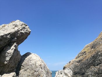 Low angle view of rock formation against clear blue sky