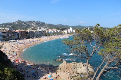 Aerial view of town by sea against blue sky