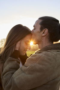 Side view of couple kissing against sky