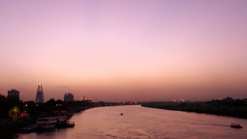Scenic view of river and city against sky during sunset