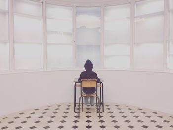 Rear view of person sitting at school desk