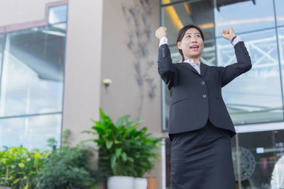 Happy businesswoman gesturing while standing in city
