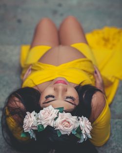 Young woman lying down on yellow flower