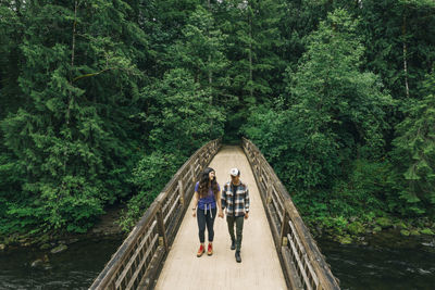 People standing on footbridge in forest