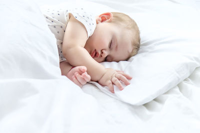 Side view of cute baby girl sleeping on bed at home