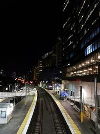 Light trails on railroad tracks against clear sky at night