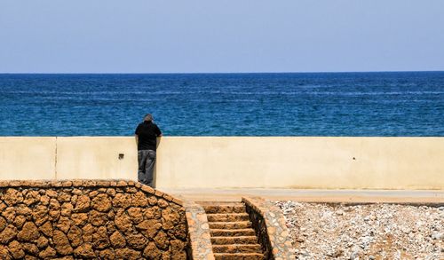 Man standing on footpath in front of sea