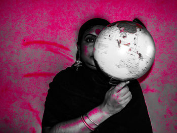 Portrait of woman holding pink rose against wall