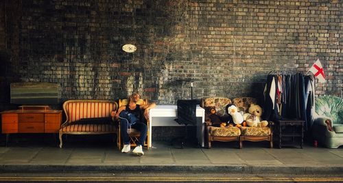 People sitting on bench against brick wall