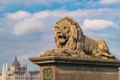 The lion from the chain bridge with the government palace in pest