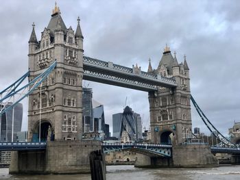 Low angle view of bridge over river against cloudy sky