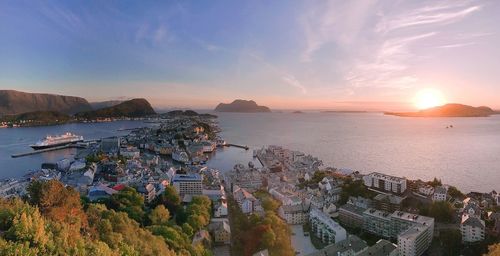 High angle view of sea and buildings against sky at sunset