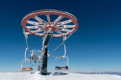 Frozen ski lift on a snowy mountain against blue sky.