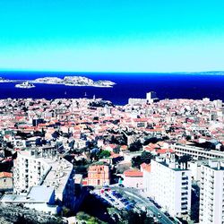 High angle view of townscape by sea against blue sky