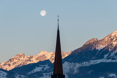 Schaan, liechtenstein, january 19, 2022 full moon in the morning behind a tower of a catholic church 