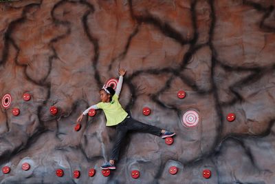 Full length of girl hanging on climbing wall