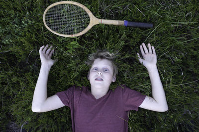 Boy lying on field with badminton racket