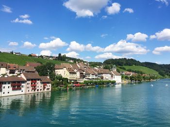 Houses by river against sky in town