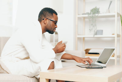 Young man using laptop while sitting on table