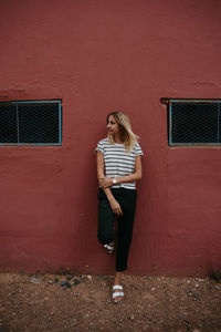 Full length of woman standing against wall