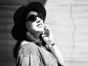 Woman wearing sunglasses against wall