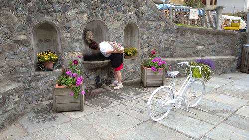 Woman sitting on potted plant by building